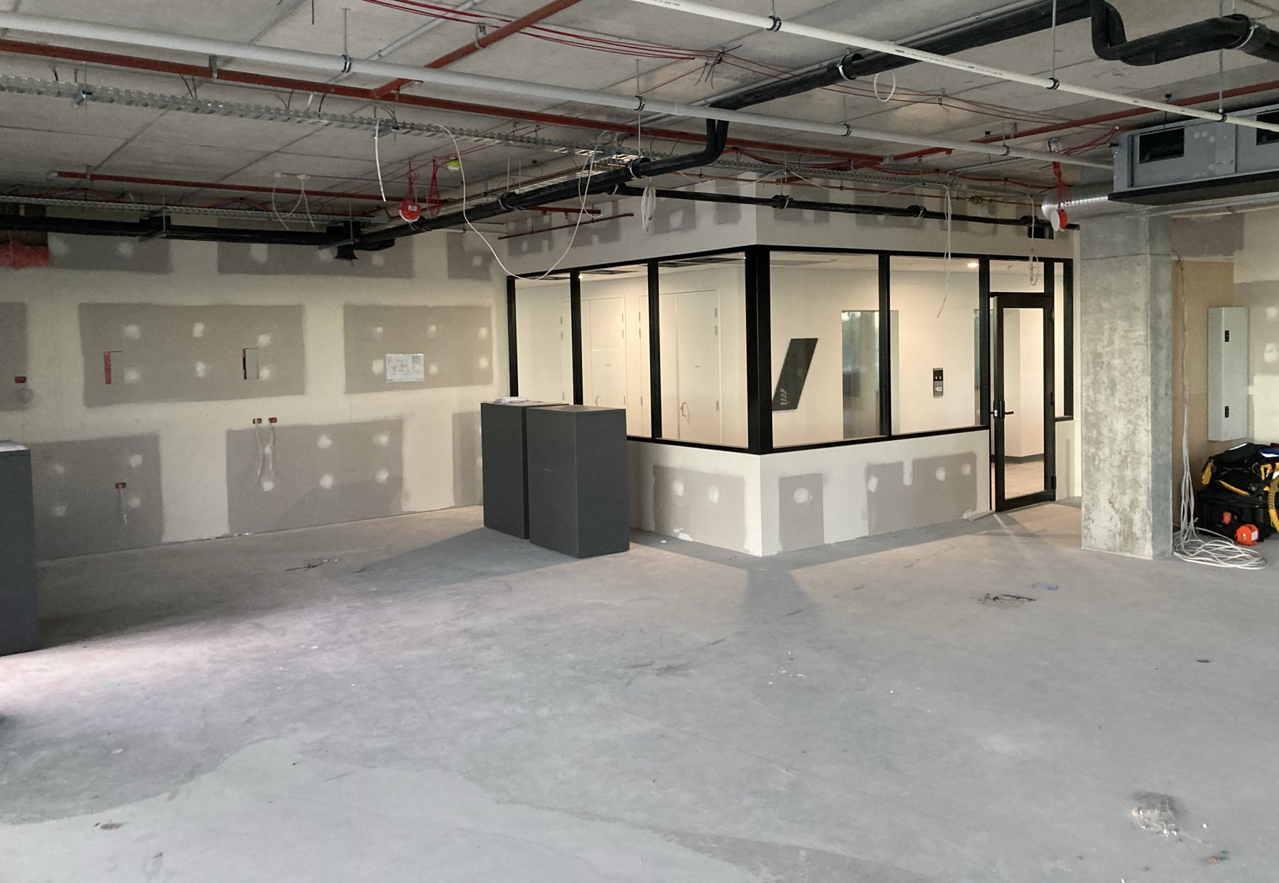 Fire sprinkler mains run through an office fit-out ceiling space.