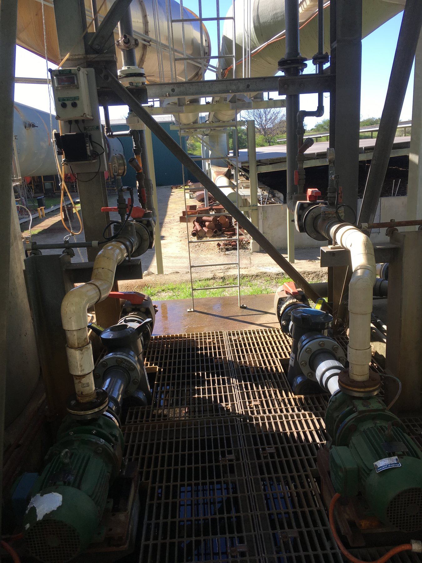 Industrial pump sets with flanged valves and pipework on a grated plant platform.
