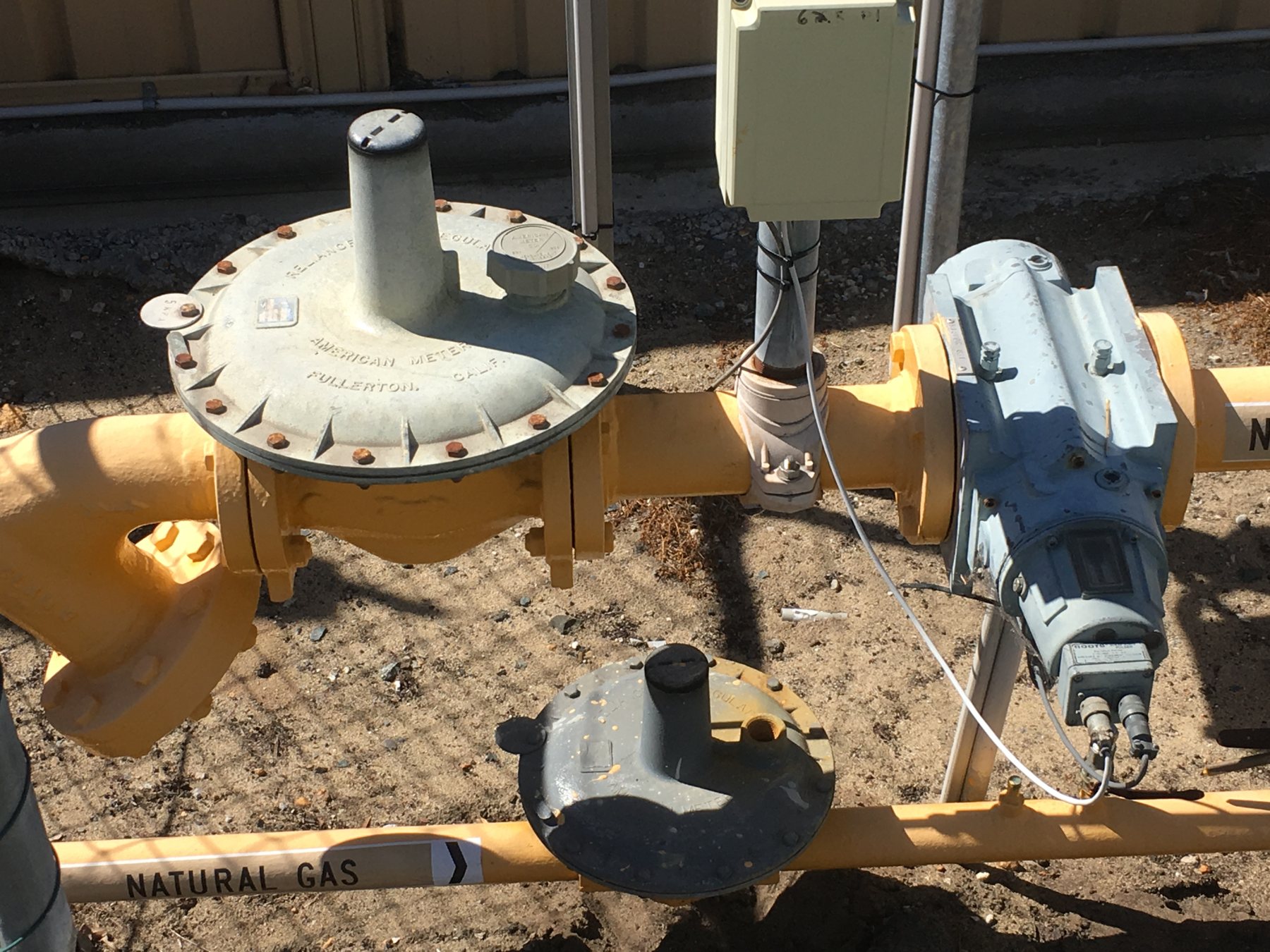 Natural gas meter and regulator set with yellow gas line identification.